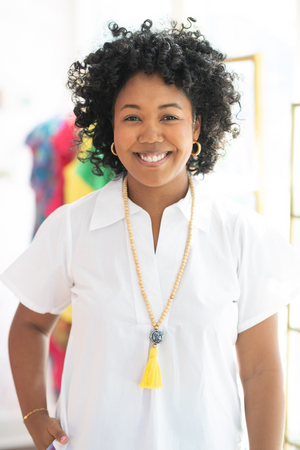 Model wearing wood beaded necklace with gold accents, porcelain chinoiserie statement bead, and yellow tassel. 