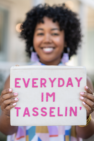 model holding white canvas pouch with the words "everyday im tasselin" in hot pink all caps block letters 