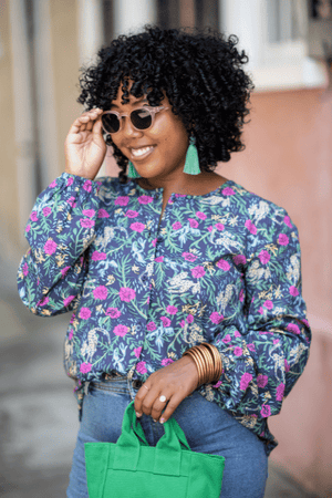Model wearing pink flora sunglasses with kelly green tassel earrings and blouse