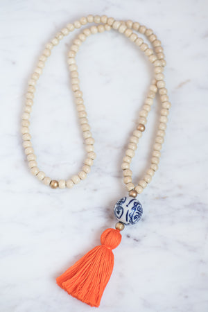 Wooden beaded necklace with golden bead accents, porcelain chinoiserie bead, and orange tassel