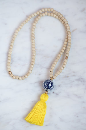 Wooden beaded necklace with golden bead accents, porcelain chinoiserie bead, and yellow tassel
