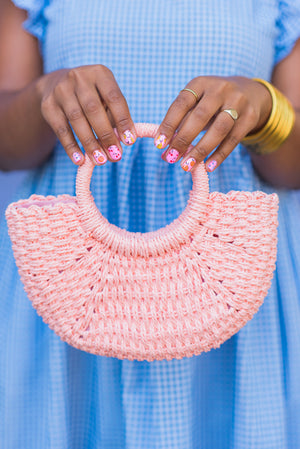 Model holding pink woven half moon bag with circular handle
